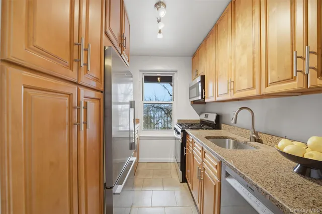 a kitchen with stainless steel appliances granite countertop a sink and a refrigerator