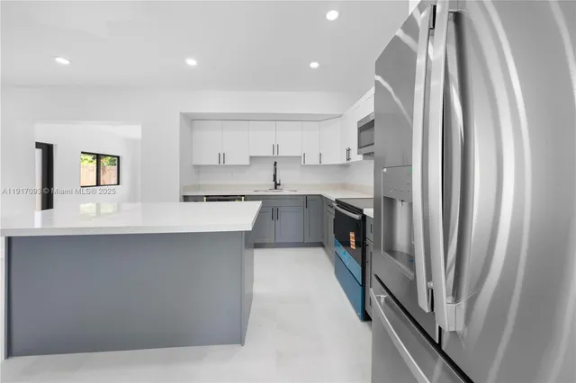 a large kitchen with a sink stainless steel appliances and cabinets
