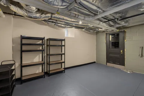 a view of an empty room with kitchen and window