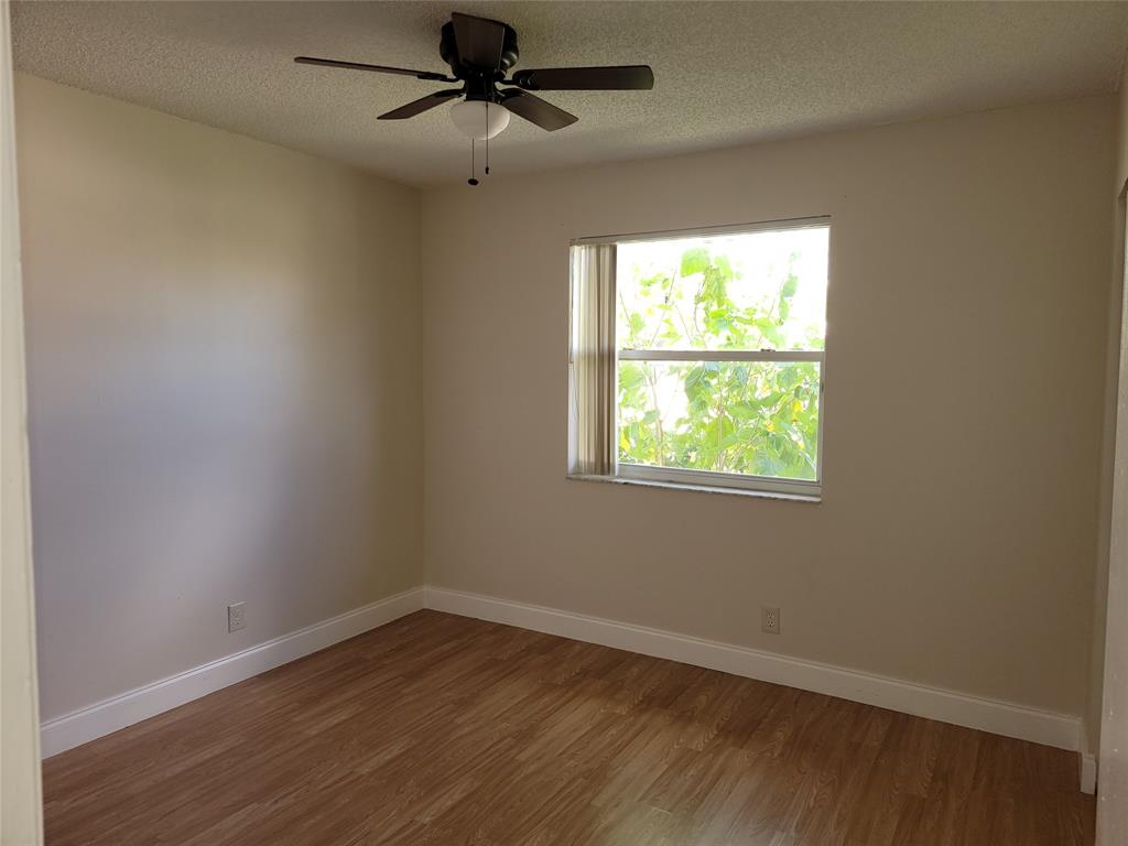 12255 Royal Palm Boulevard, Unit 8O Coral Springs, FL 33065 - Photo 11 of 15 an empty room with wooden floor ceiling fan and windows
