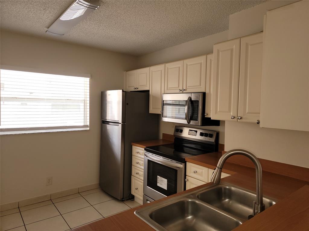 12255 Royal Palm Boulevard, Unit 8O Coral Springs, FL 33065 - Photo 8 of 15 a kitchen with a refrigerator a stove a sink and a microwave
