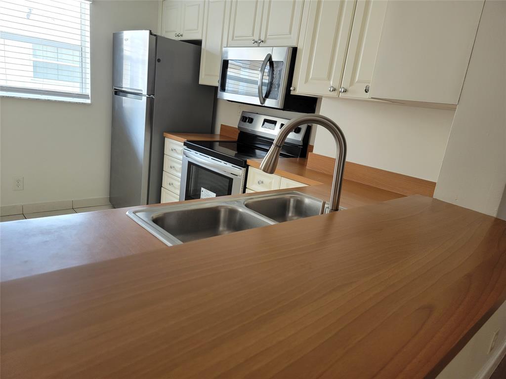 12255 Royal Palm Boulevard, Unit 8O Coral Springs, FL 33065 - Photo 9 of 15 a kitchen with stainless steel appliances granite countertop a refrigerator a sink a stove and white cabinets