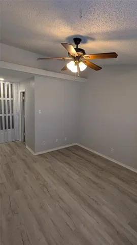 an empty room with wooden floor chandelier fan and windows