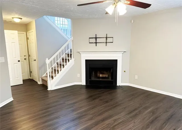 a view of an empty room with wooden floor fireplace and a window