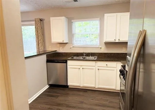 a kitchen with granite countertop a refrigerator sink and cabinets