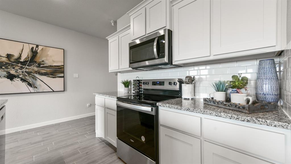 a kitchen with granite countertop white cabinets and black stainless steel appliances