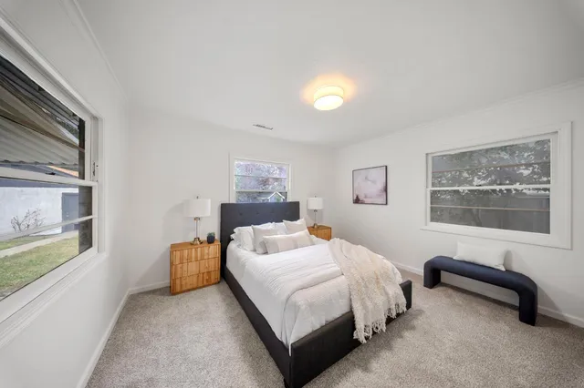 a bedroom with a bed lamp and paintings on the wall