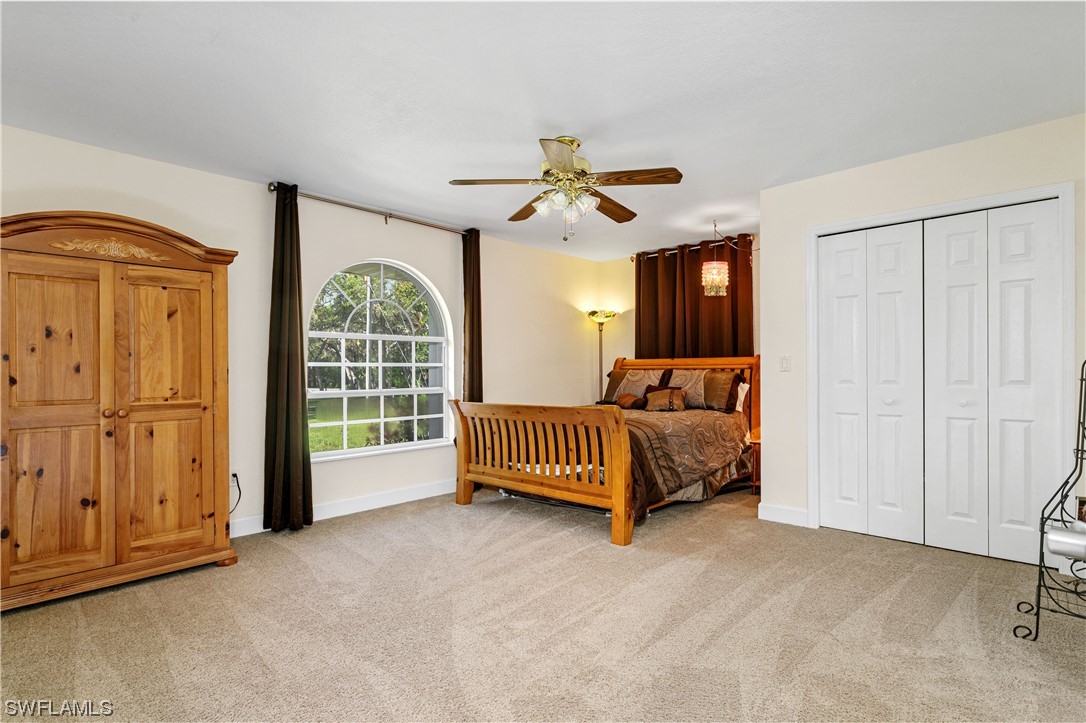 17571 Oak Creek Road Alva, FL 33920 - Photo 21 of 49 a spacious bedroom with a bed and a chandelier
