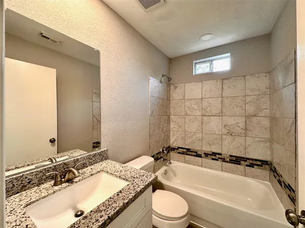 a bathroom with a granite countertop tub sink and mirror