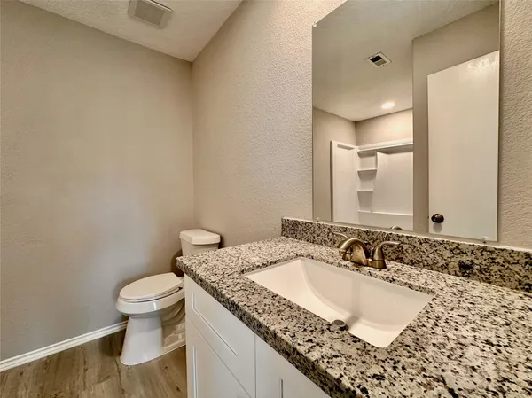 a bathroom with a granite countertop sink a toilet and a mirror