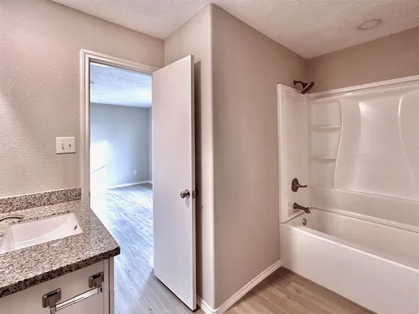 a bathroom with a granite countertop sink and mirror with bathtub