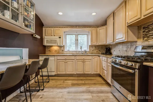 a kitchen with granite countertop a stove chairs sink and cabinets