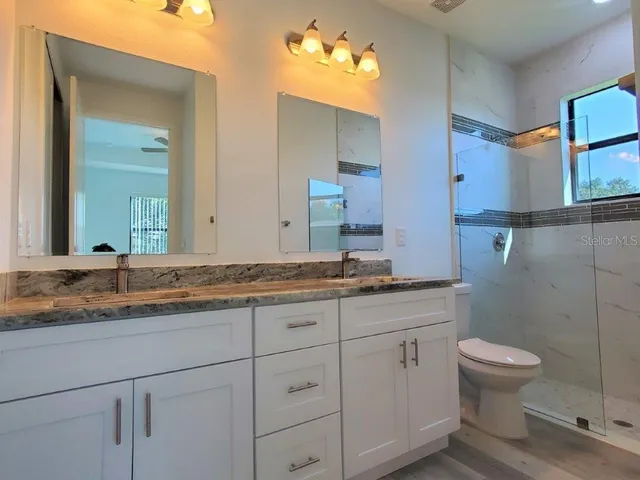 a bathroom with a granite countertop toilet a sink and mirror