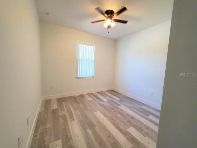 an empty room with a window and a ceiling fan