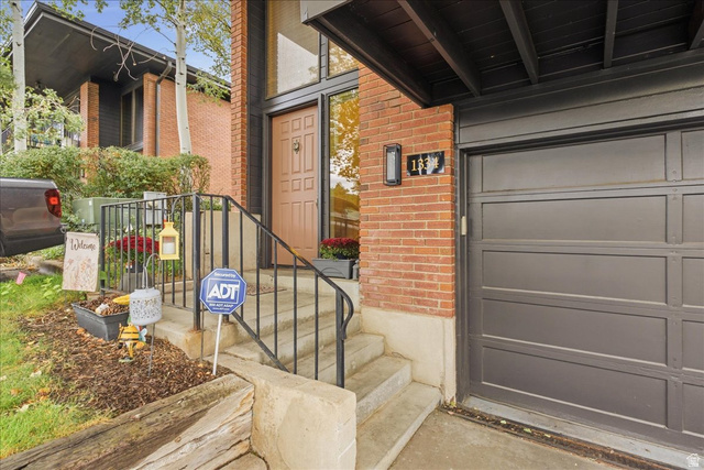 1334 Ridgewood Lane Bountiful, UT 84010 - Photo 4 of 38 Brick exterior with an attached garage, concrete steps, and a wrought iron handrail leading to the entrance