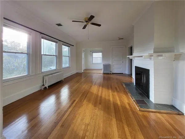 a view of an empty room with wooden floor and a window