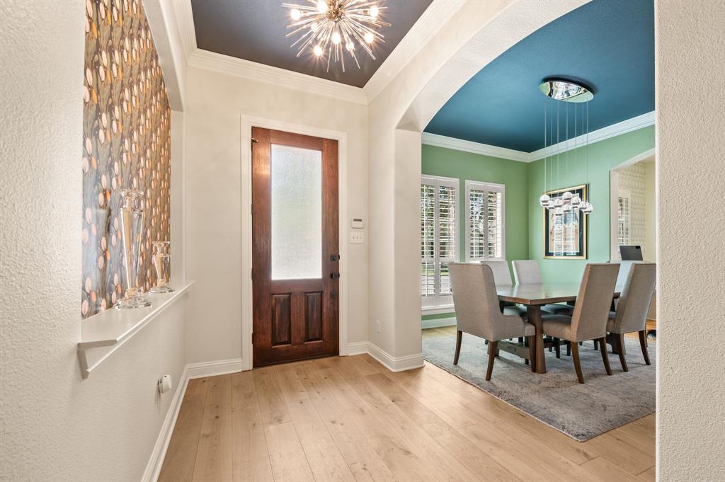 1521 Newton Ranch Road Keller, TX 76248 - Photo 3 of 40 Light wood flooring throughout, solid wood entry door with frosted glass panel, recessed decorative wall niche, arched doorway, and plantation shutters