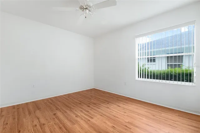 a view of empty room with wooden floor and fan