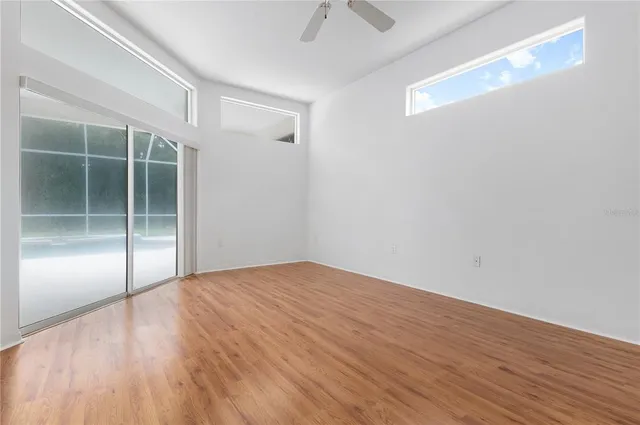 a view of empty room with wooden floor and fan