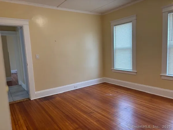a view of an empty room with wooden floor and a window