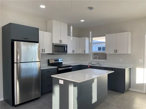 a kitchen with a sink a refrigerator a microwave and cabinets