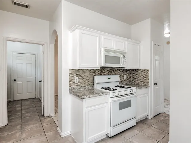 a kitchen with white cabinets and white appliances