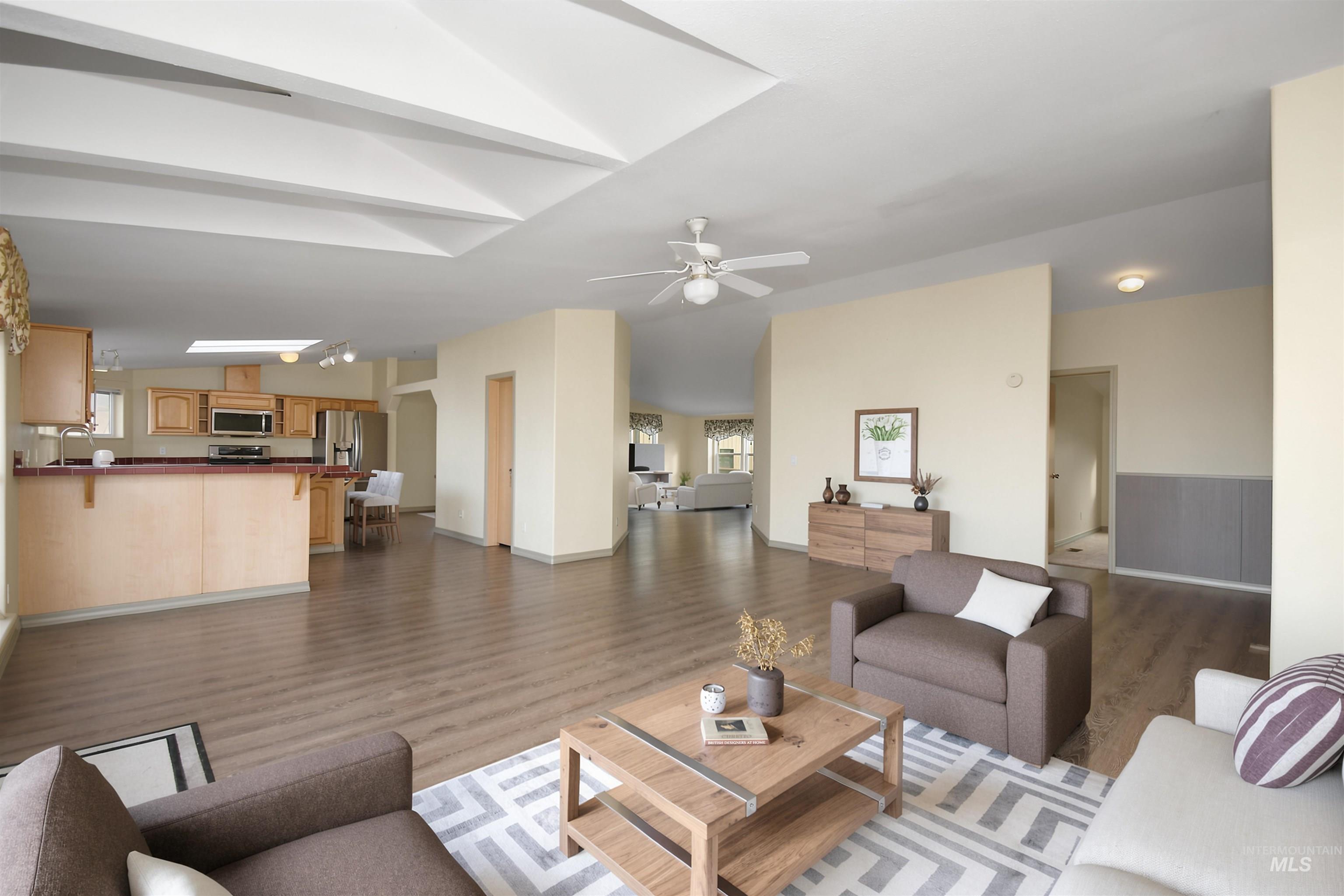 11375 Timber Butte Road Sweet, ID 83670 - Photo 16 of 49 Open-concept living area featuring wood-finish flooring, a kitchen with light wood cabinetry and stainless steel appliances, a breakfast bar with a red countertop, and a ceiling fan