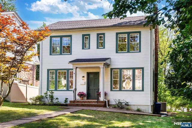 a view of a brick house with large windows and a large tree