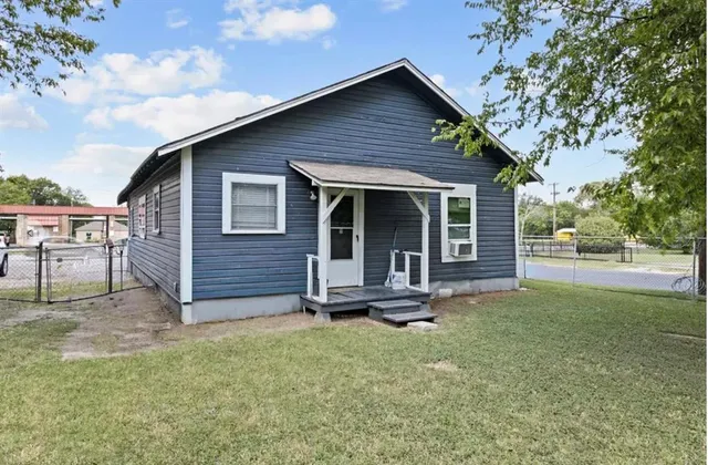 a front view of a house with a garden and trees