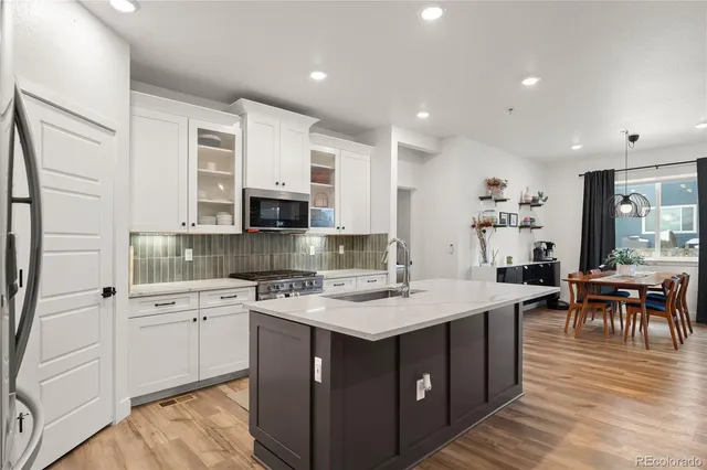 a kitchen with a sink stove cabinets and wooden floor