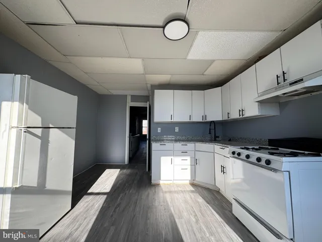 a kitchen with granite countertop a stove a sink dishwasher and a refrigerator with wooden floor