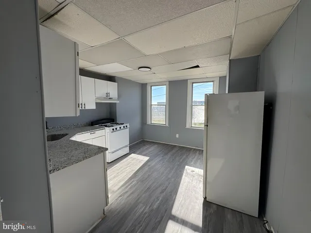 a kitchen with granite countertop white cabinets and white appliances