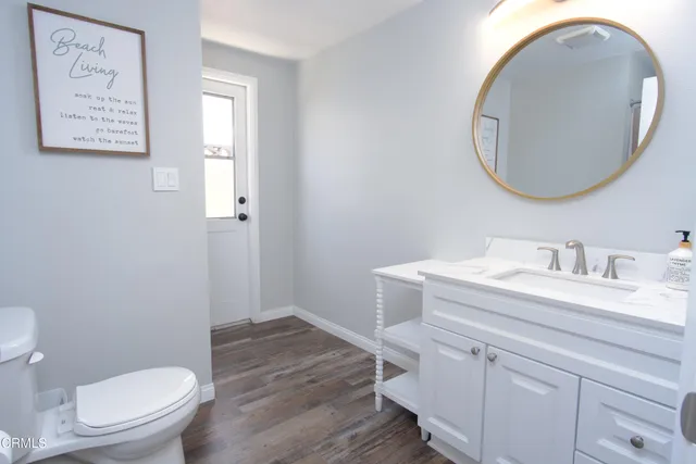 a bathroom with a granite countertop toilet a sink and a mirror