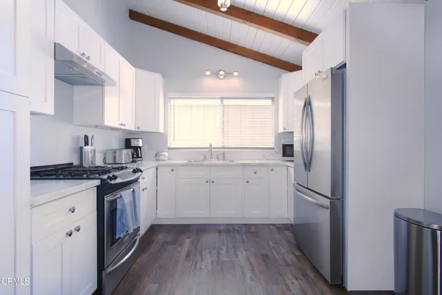 a kitchen with granite countertop stainless steel appliances a sink cabinets and a window
