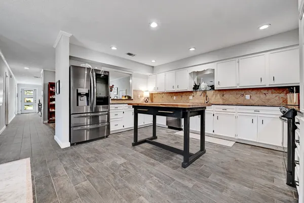 a kitchen with stainless steel appliances kitchen island granite countertop a refrigerator and a stove top oven