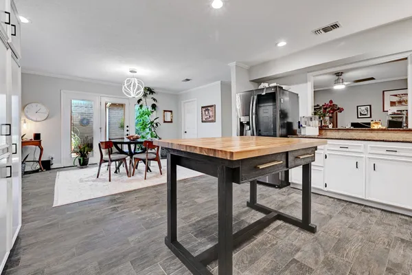 a kitchen with stainless steel appliances kitchen island granite countertop a table chairs sink and cabinets