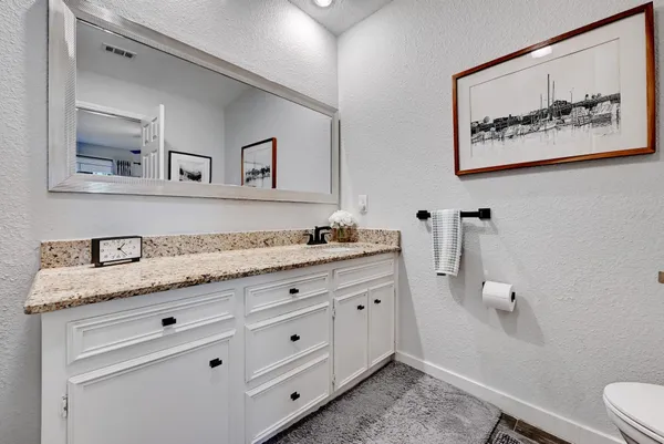 a bathroom with a granite countertop toilet sink and mirror