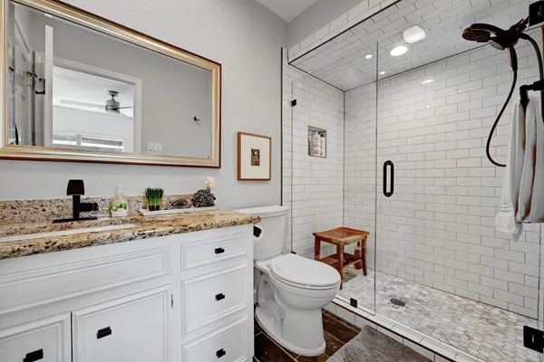 a bathroom with a granite countertop sink mirror vanity and toilet