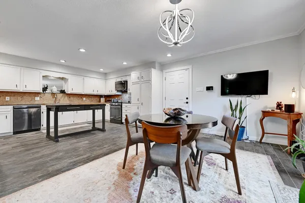 a view of a dining room with furniture a kitchen and chandelier