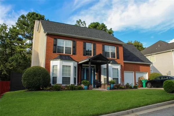 a front view of a house with a yard and trees