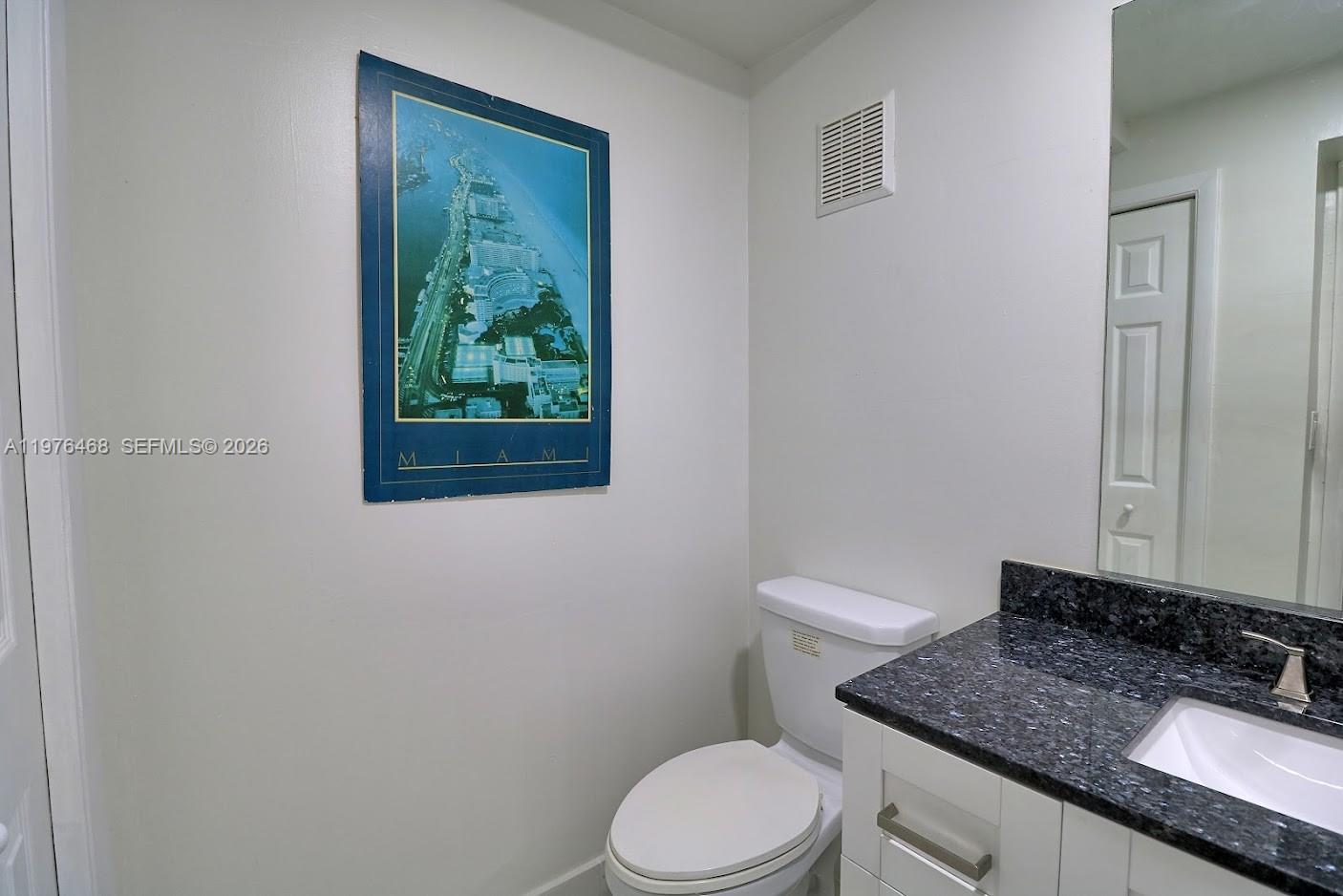 16500 Golf Club Road, Unit 205 Weston, FL 33326 - Photo 14 of 18 a bathroom with a granite countertop toilet a mirror and a sink