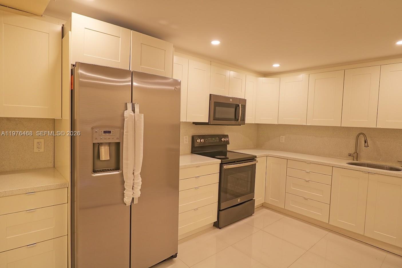 16500 Golf Club Road, Unit 205 Weston, FL 33326 - Photo 7 of 18 a kitchen with white cabinets and refrigerator