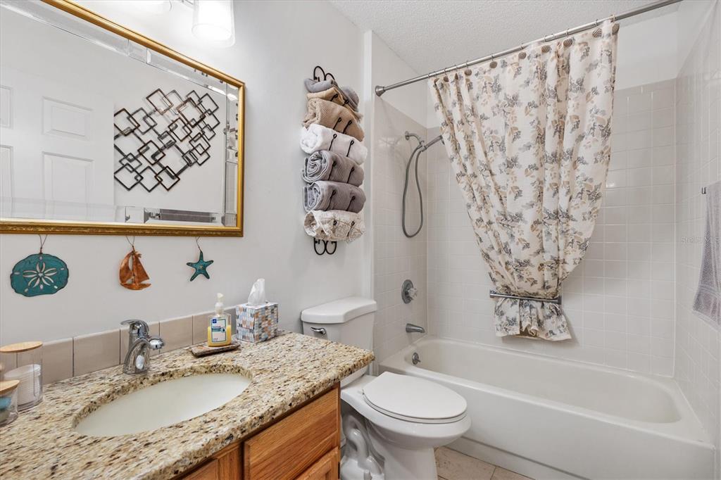 711 Agua Way Lady Lake, FL 32159 - Photo 11 of 16 a bathroom with a granite countertop sink a toilet and a bathtub
