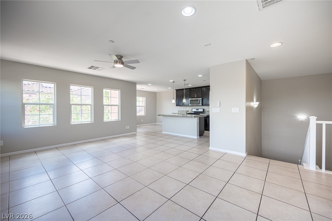 9916 Sable Point Street Las Vegas, NV 89178 - Photo 27 of 73 A spacious, naturally illuminated living area transitions smoothly into a modern kitchen, featuring recessed and pendant lighting.