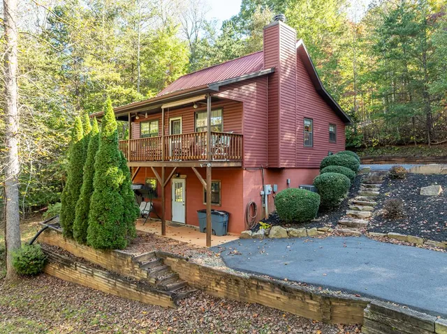 a view of a house with a yard plants and large tree