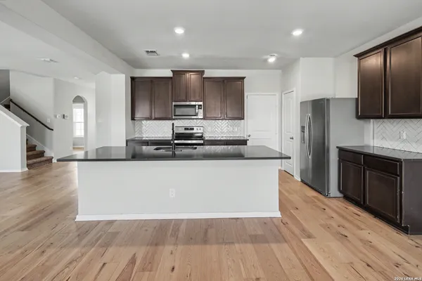 a large kitchen with stainless steel appliances granite countertop a stove a refrigerator a sink and a oven with wooden floor