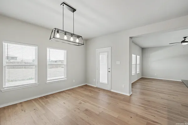 an empty room with wooden floor windows and ceiling fan