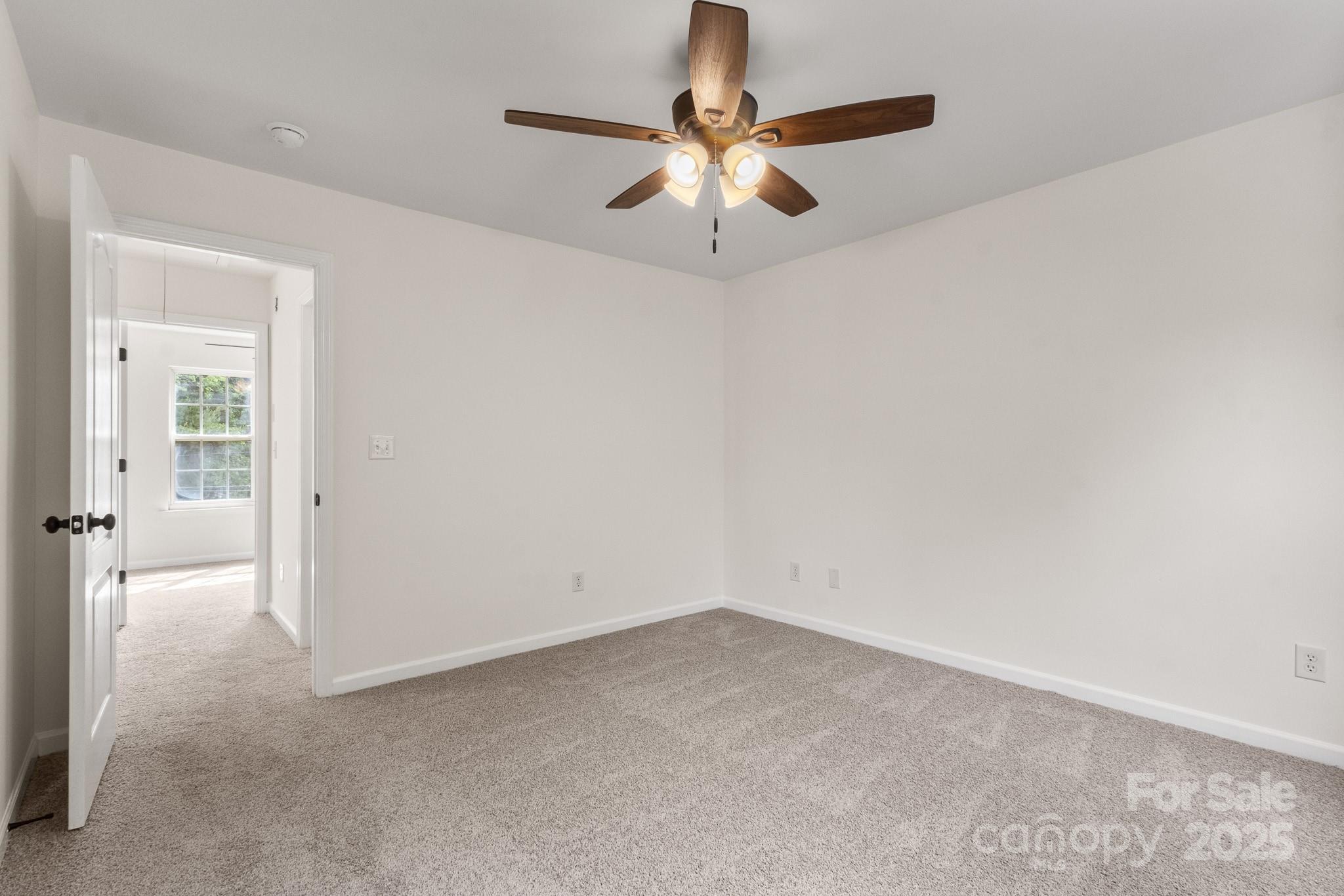 5529 Seths Drive Charlotte, NC 28269 - Photo 22 of 32 an empty room with a chandelier fan and windows