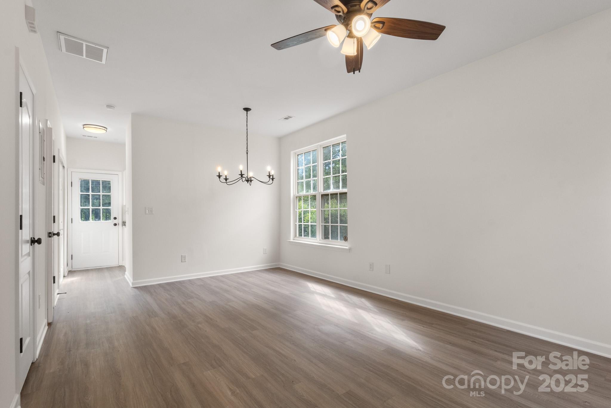 5529 Seths Drive Charlotte, NC 28269 - Photo 4 of 32 an empty room with wooden floor chandelier fan and windows