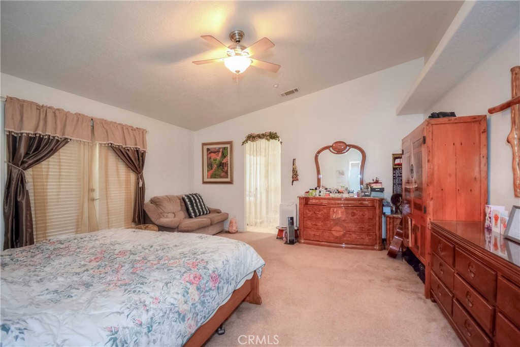 9331 Manada Road Phelan, CA 92371 - Photo 16 of 38 a bedroom with a large bed and a chandelier